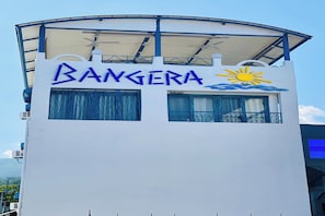 Ein Gebäude mit einem Schild, auf dem 'BANGERA' und ein Sonnensymbol stehen, das ein Hotel oder Resort kennzeichnet.