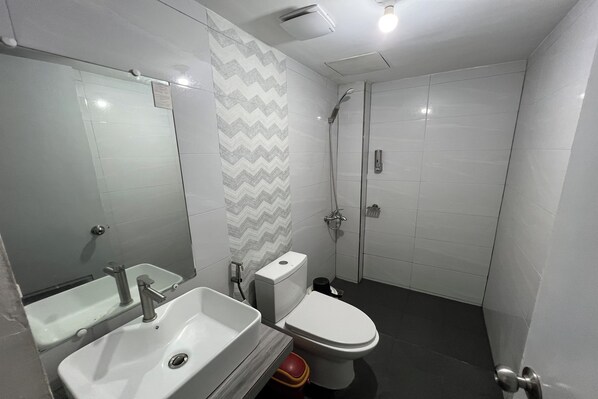 Un baño con lavabo, inodoro, ducha y espejo.
