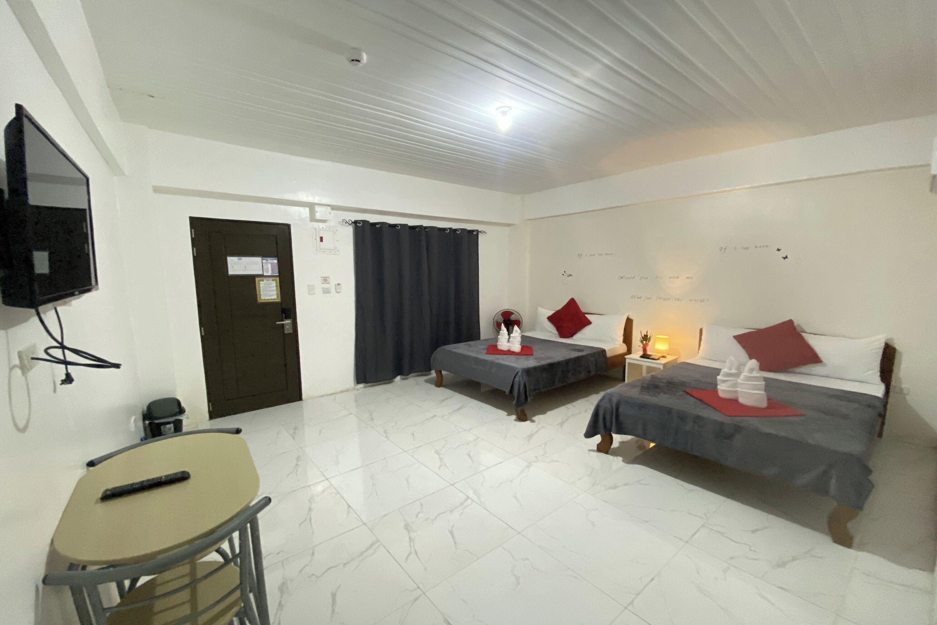 A hotel room with two beds, a TV, a desk, and a chair.