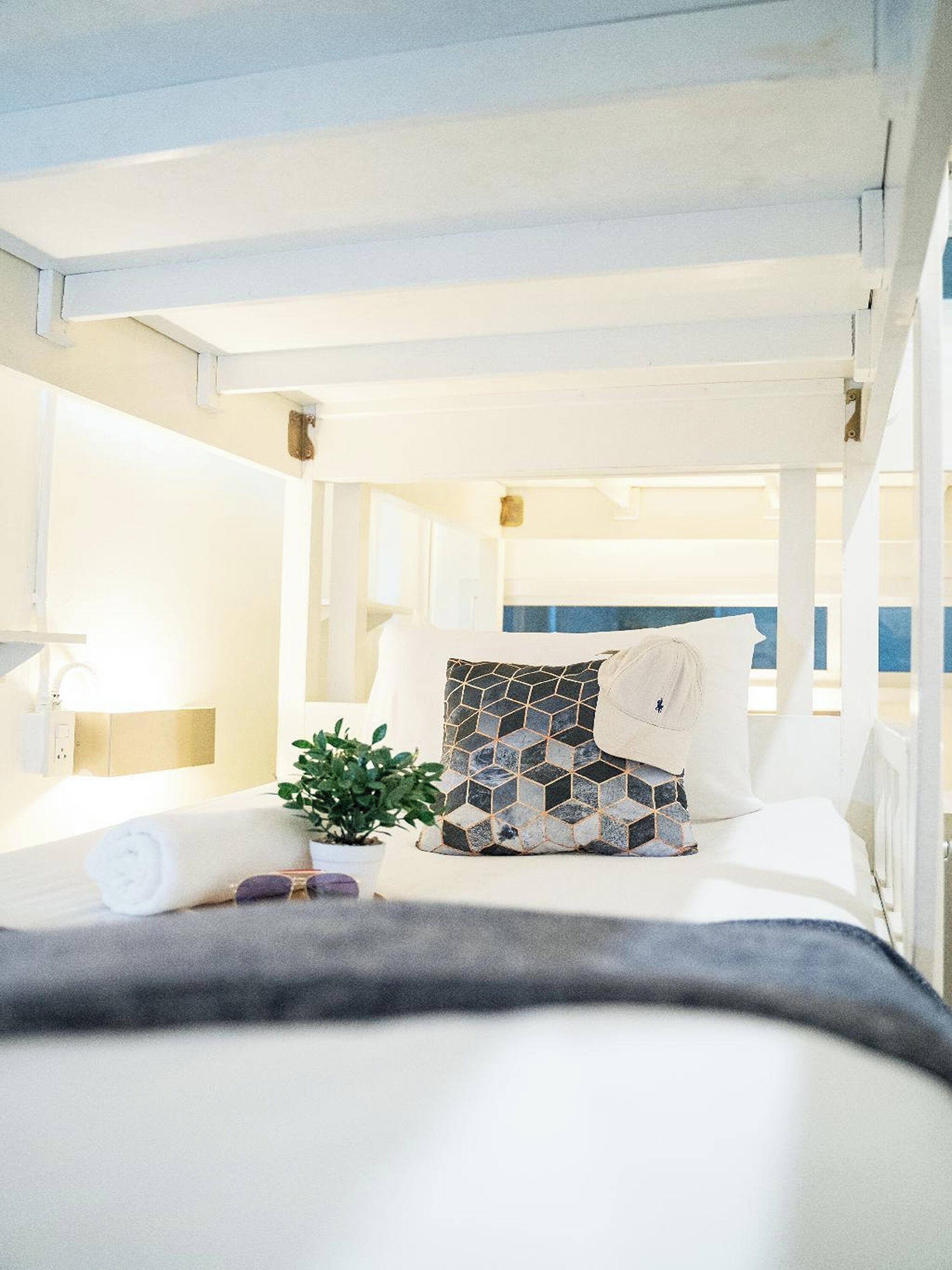 Habitación de hotel con cama, planta en maceta, toalla y vista al mar.