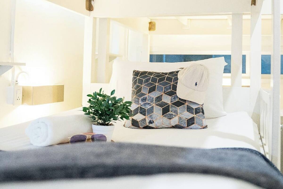 A hotel room with a bed, a potted plant, a towel, and a view of the sea.