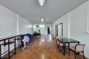 A spacious room with a long wooden floor, a desk with a computer, a chair, and a fan. - Hostel Happy Elephant (Chiang Mai)