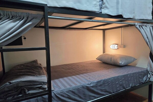 A bunk bed with a single bed on the lower bunk, a pillow, and a wall-mounted light fixture. - Hostel Happy Elephant (Chiang Mai)