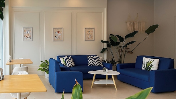 Un salon moderne avec un canapé bleu, une table basse ronde et une petite table à manger.