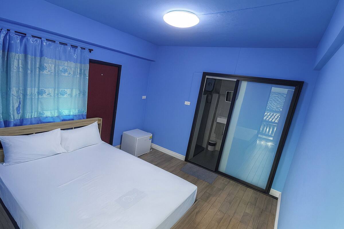 Een slaapkamer met een bed, een klein nachtkastje, een verwarming en een glazen schuifdeur naar een balkon.