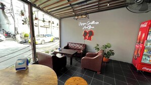 Ein gemütlicher Innenbereich mit einer Couch, Sesseln und einem Tisch. Eine Neonreklame zeigt 