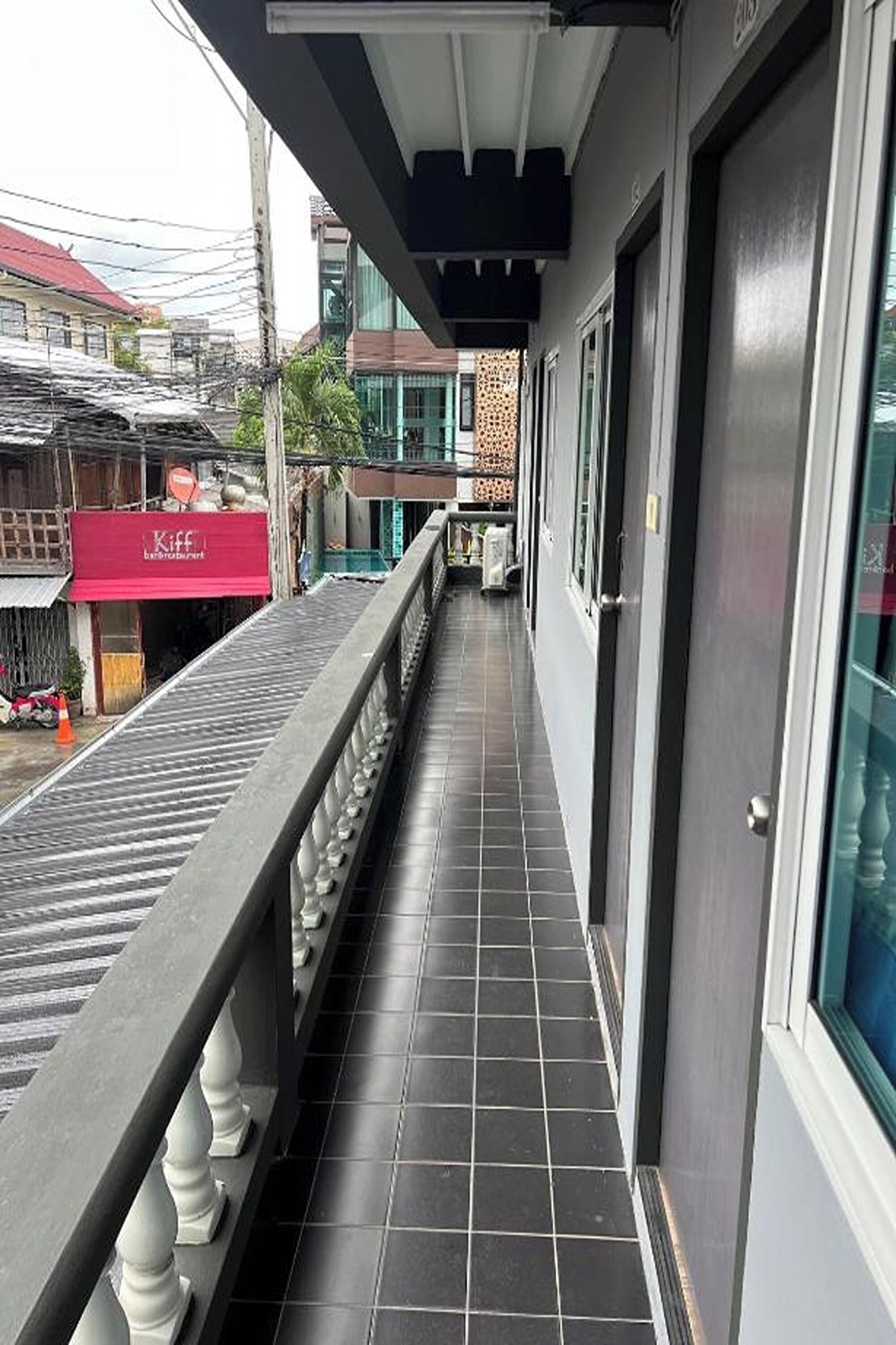 A narrow corridor with a tiled floor, a railing on one side, and a door on the other.