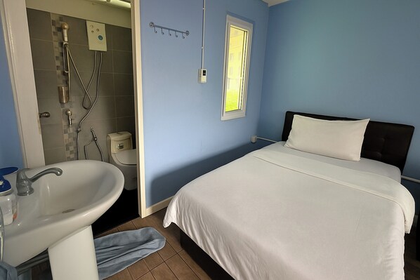 A bedroom with a bed, a window, a bathroom with a sink and shower. - The Voyager Guesthouse (Chiang Mai)