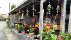 Ein Restaurant mit Außenbereich, Topfpflanzen und hängenden Dekorationen.