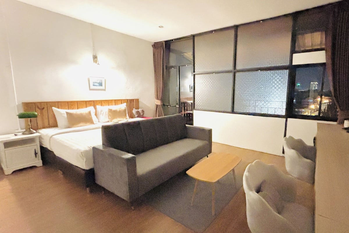 Una habitación de hotel con una cama, un sofá, una mesita y una silla.