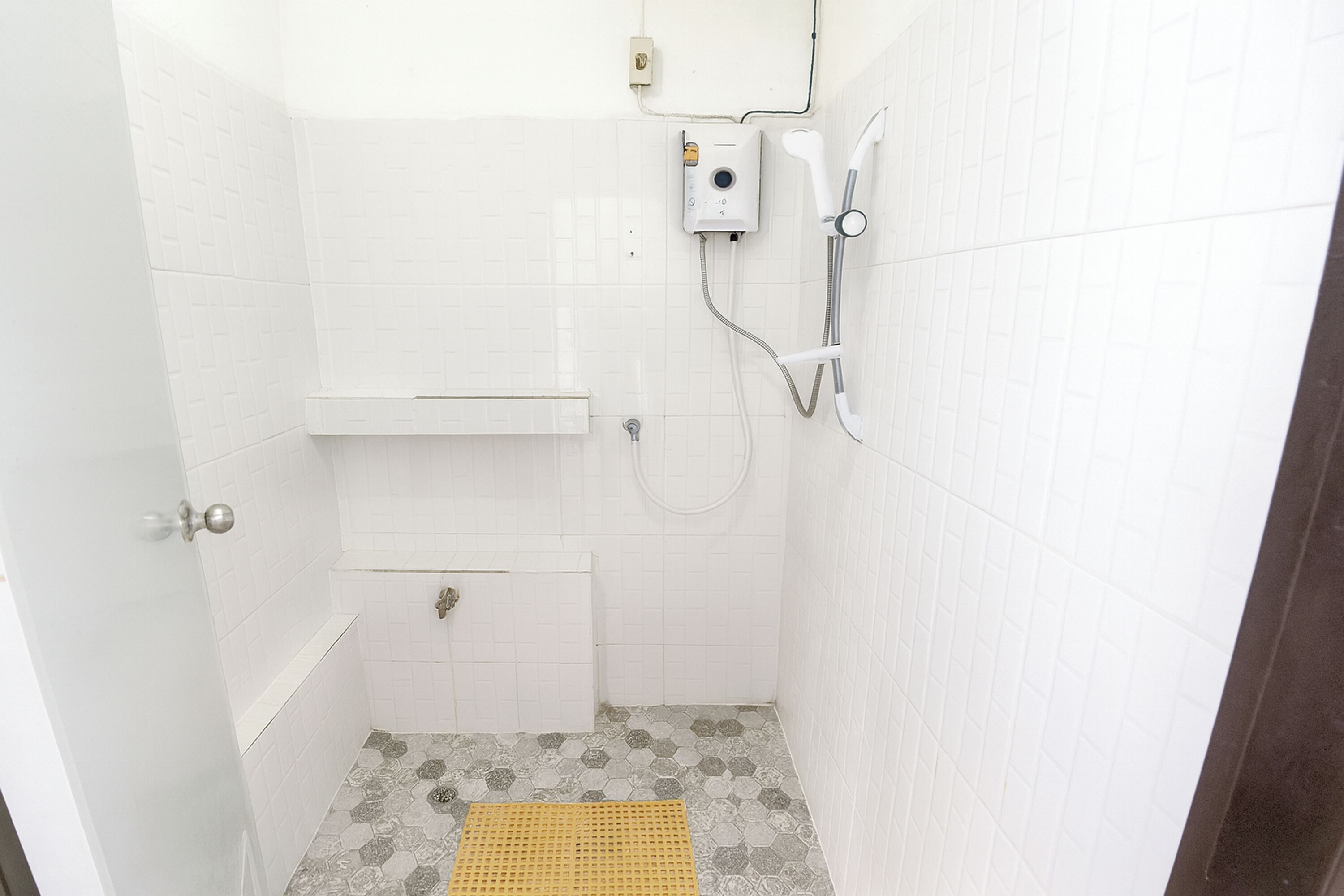 Un baño pequeño y blanco con ducha, inodoro y lavamanos.