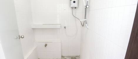 Un baño pequeño y blanco con ducha, inodoro y lavamanos.