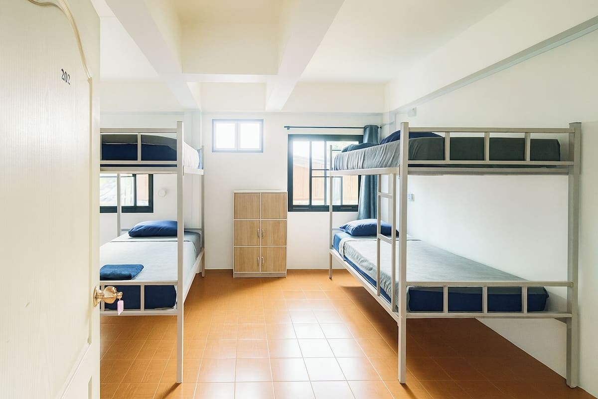 Une chambre de dortoir avec des lits superposés, une armoire et une fenêtre.