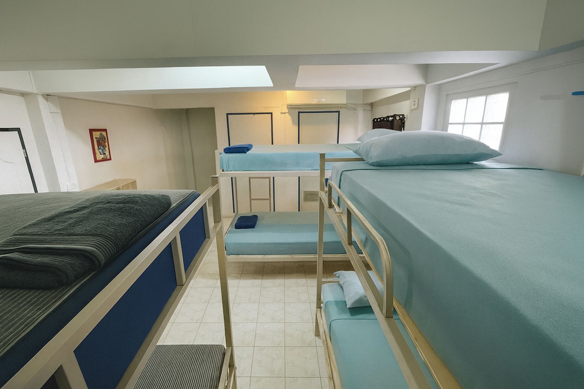 Une chambre de dortoir avec des lits superposés, un petit bureau et une fenêtre.