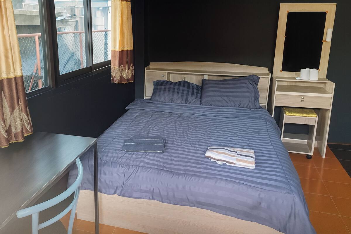 Une chambre à coucher comprenant un lit, un bureau, une chaise, une commode et un miroir.