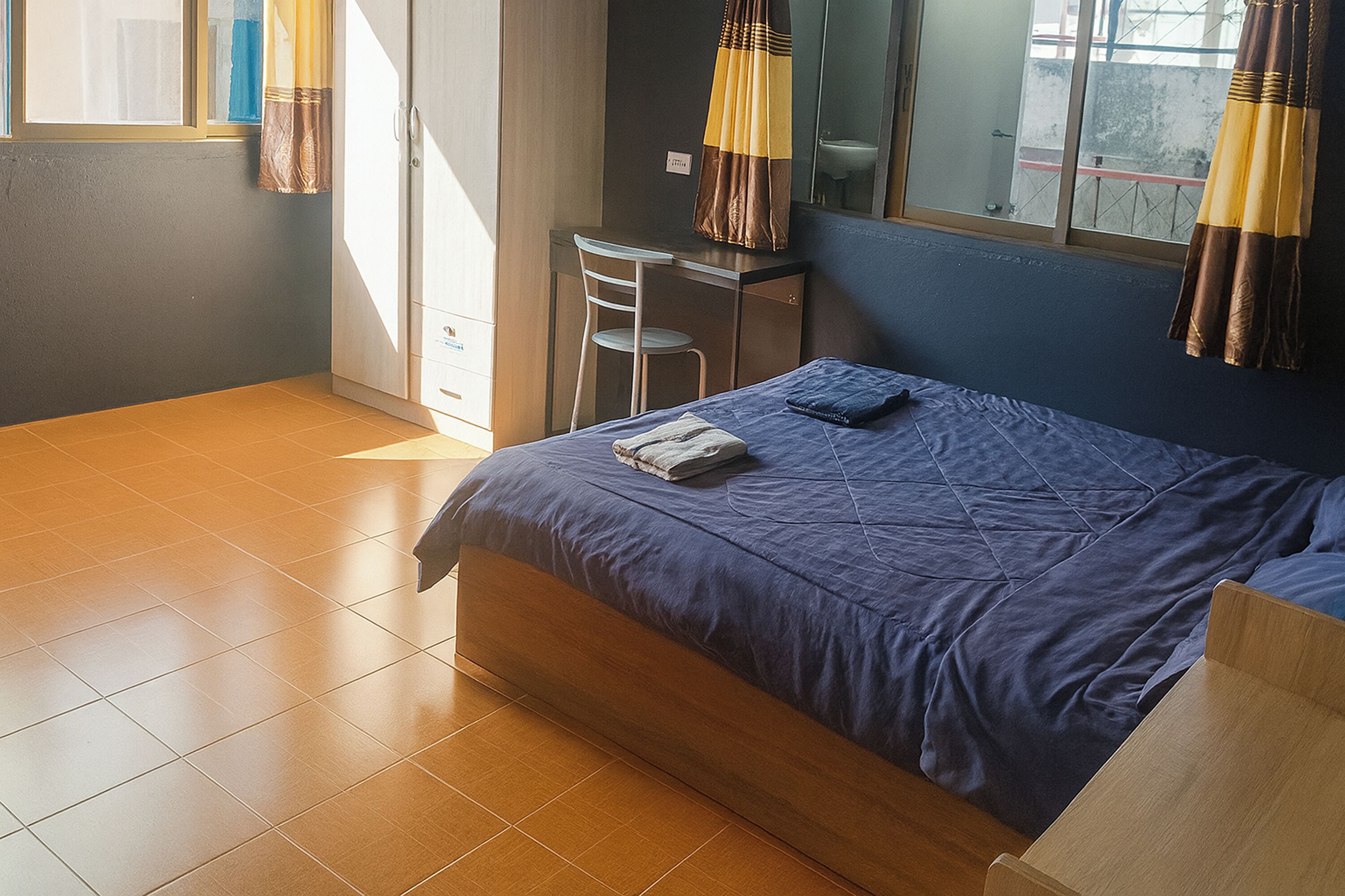 A bedroom with a bed, a desk, and a chair.