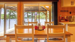 A wooden dining table with two chairs, a red mug, and a coffee pot. - Steenburg Shores & S'mores (Gilmour)