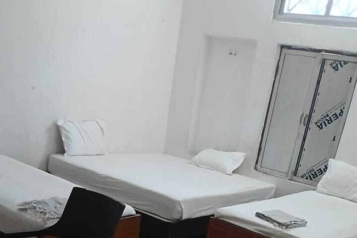 A dormitory room with two beds, a desk, and a chair.