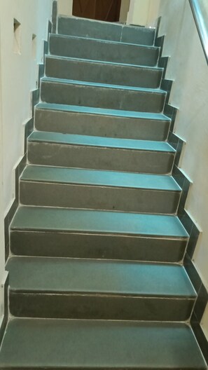 A set of dark grey, wide stairs with a handrail on the right side, leading upwards. - Rai Residency (Varanasi)