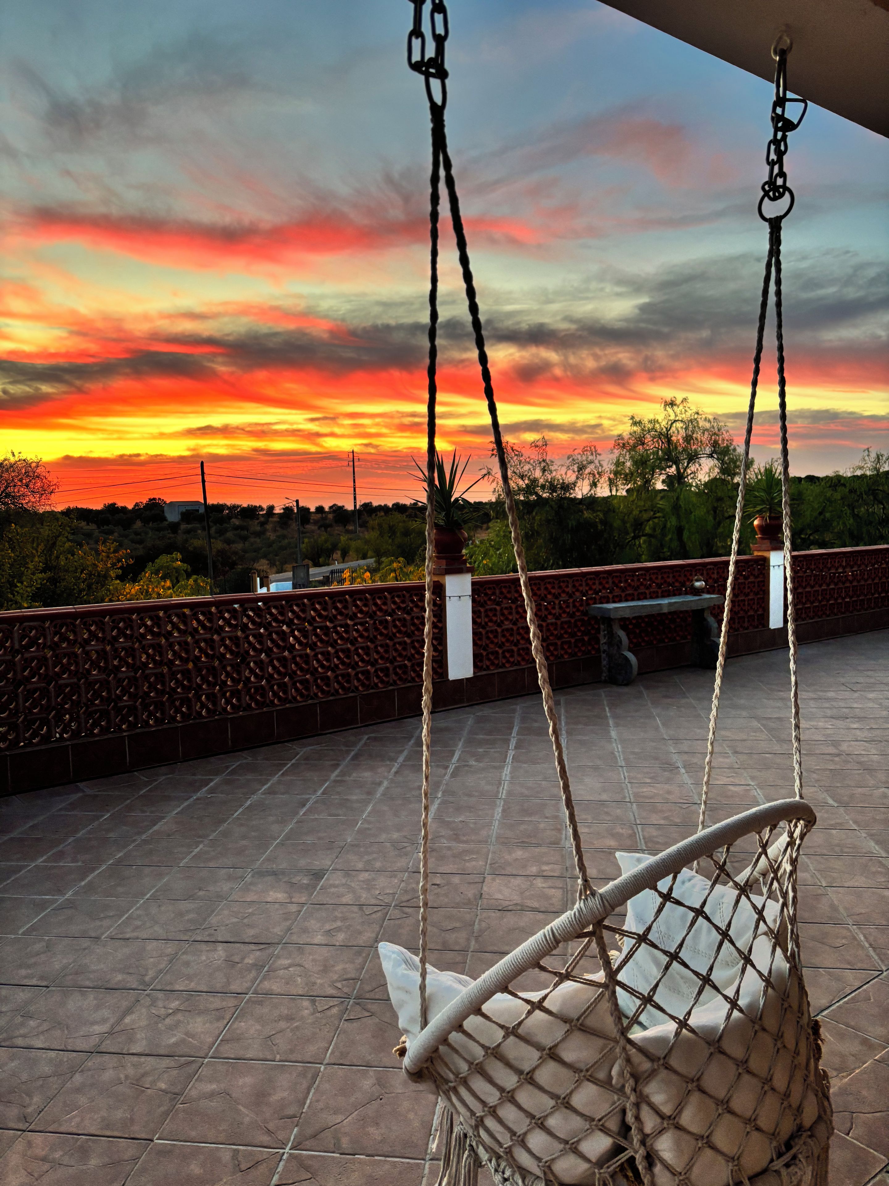 A hammock on a tiled patio with a sunset view.