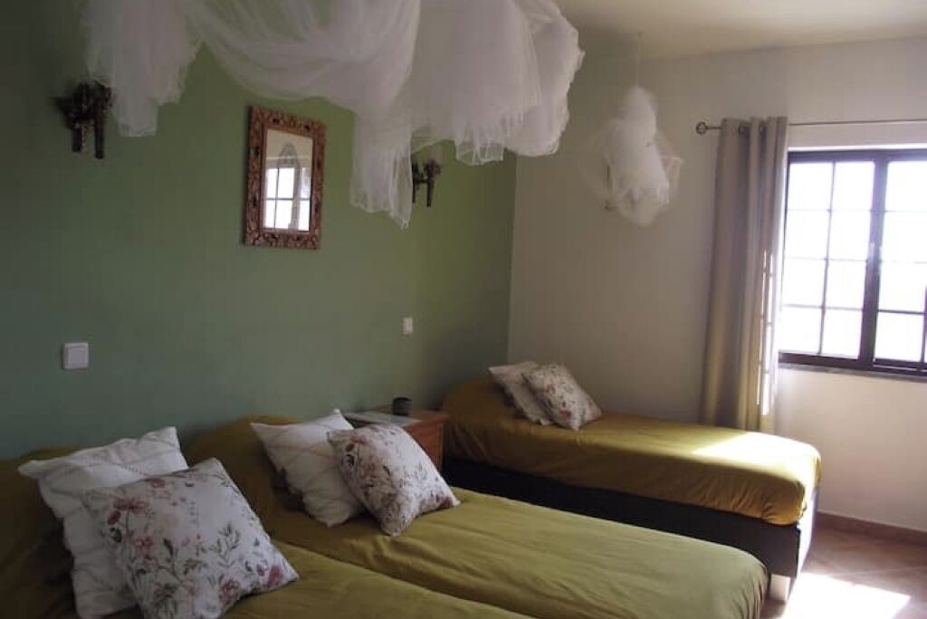 Una habitación con dos camas, un espejo y una ventana con cortinas.