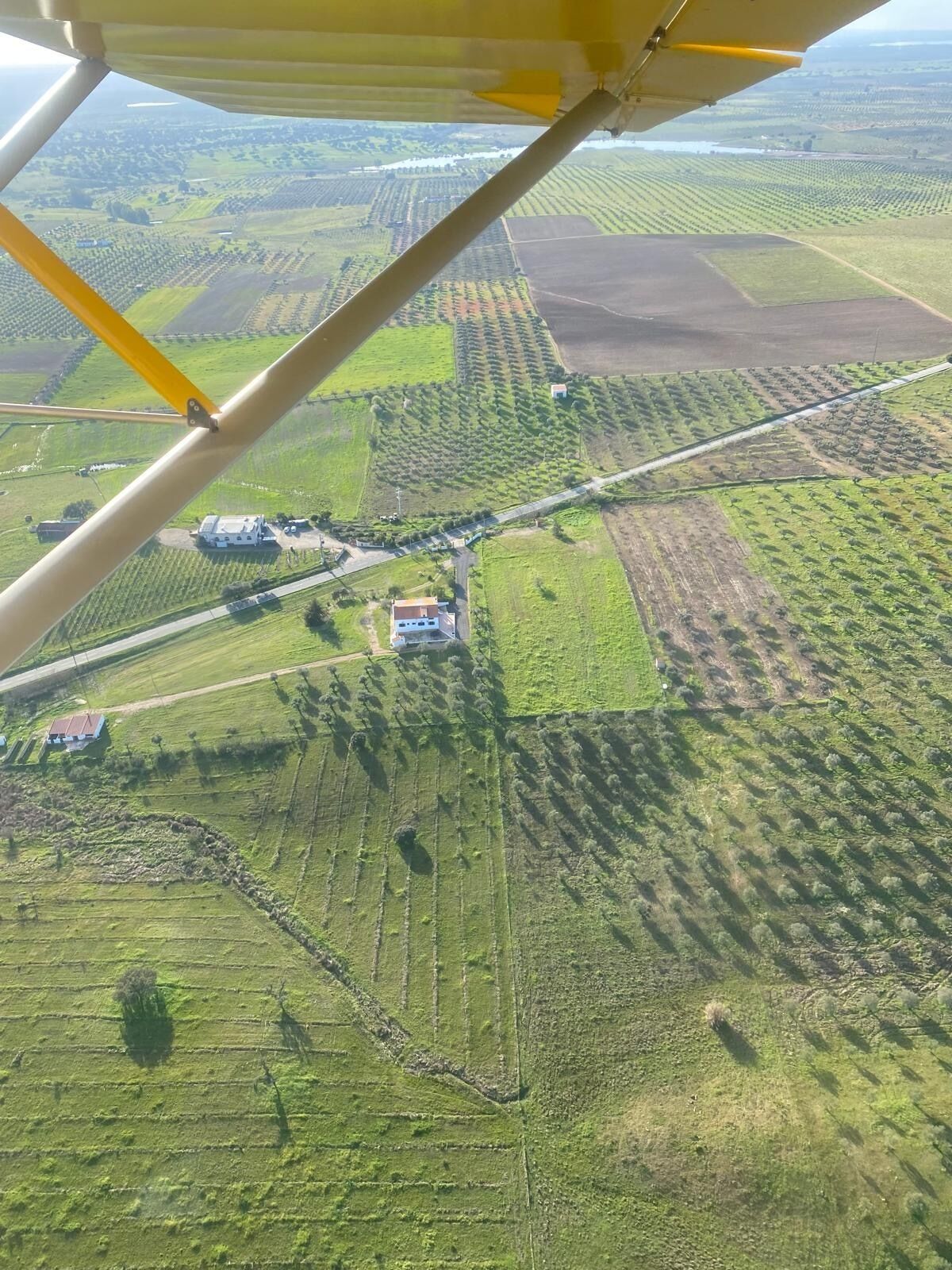 An aerial view of a rural landscape with fields, a road, and a small building.