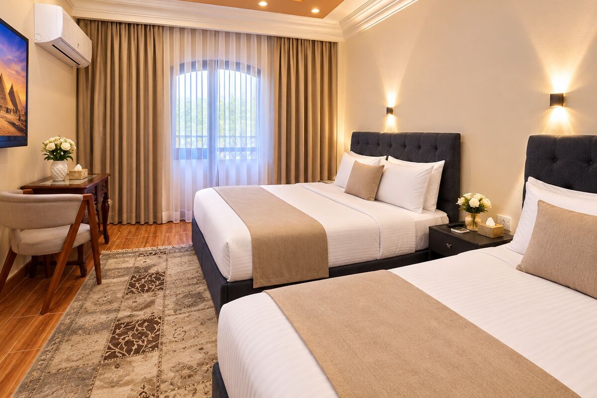 Habitación de hotel con dos camas, un escritorio, una silla, un ventanal con cortinas y un aire acondicionado instalado en la pared.