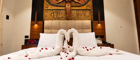 Ein Hotelzimmer mit einem Bett, Wandgemälde, einer Uhr und einem Nachttisch.
