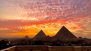 A view of the pyramids at sunset with a clear sky. - Pyramids Kingdom RZ Hotel  (Giza)