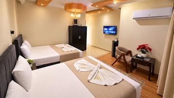 A hotel room with two beds, a desk, a chair, a television, and an air conditioning unit.