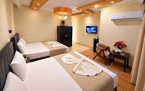 A hotel room with two beds, a desk, a chair, a television, and an air conditioning unit. - Queens Isis Pyramids View (Giza)