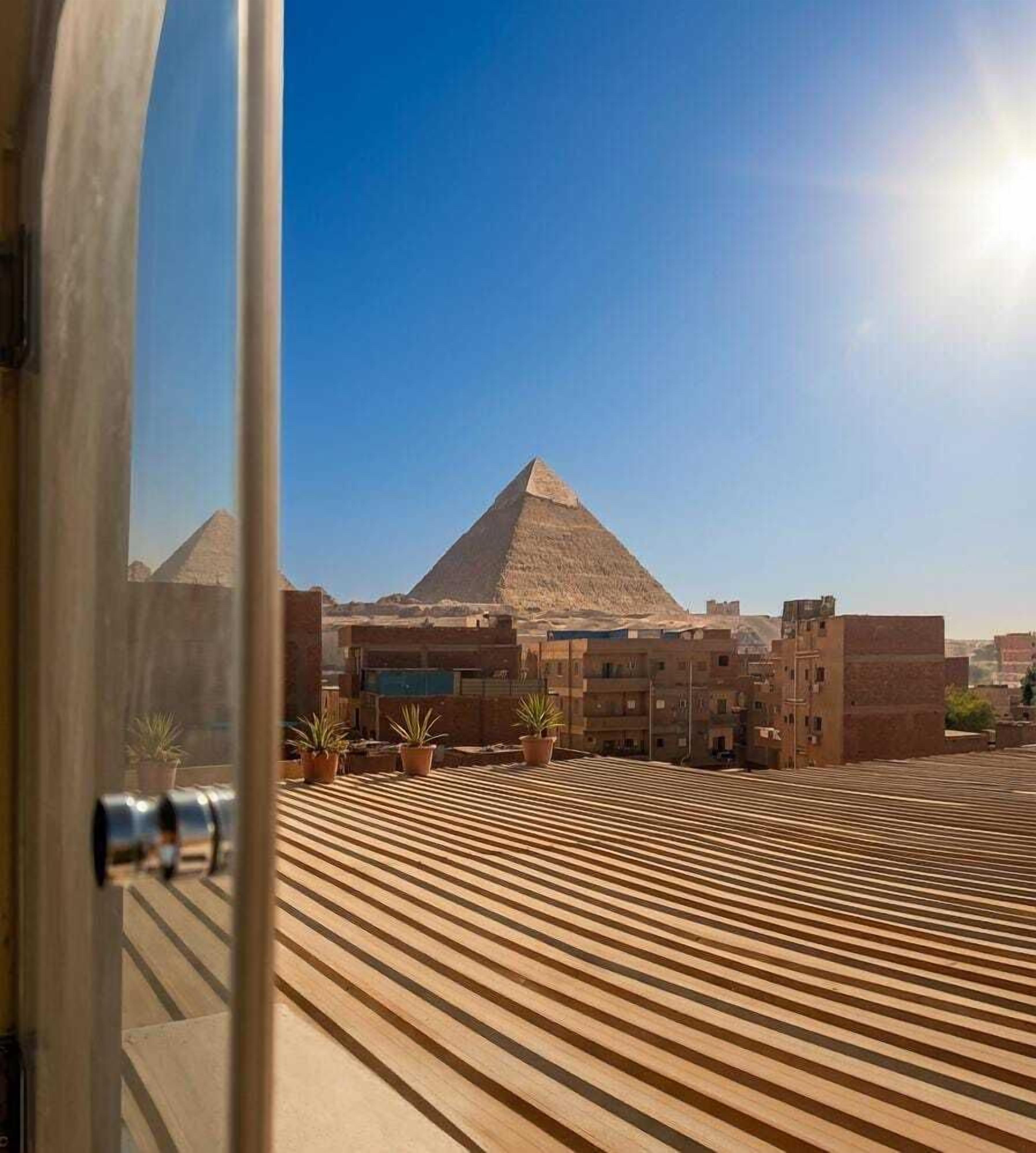A view from inside a building with a wooden floor pattern, a door, and a clear sky.