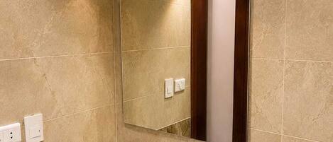 A bathroom with a white sink, a mirror, a hairdryer, and a towel rack.