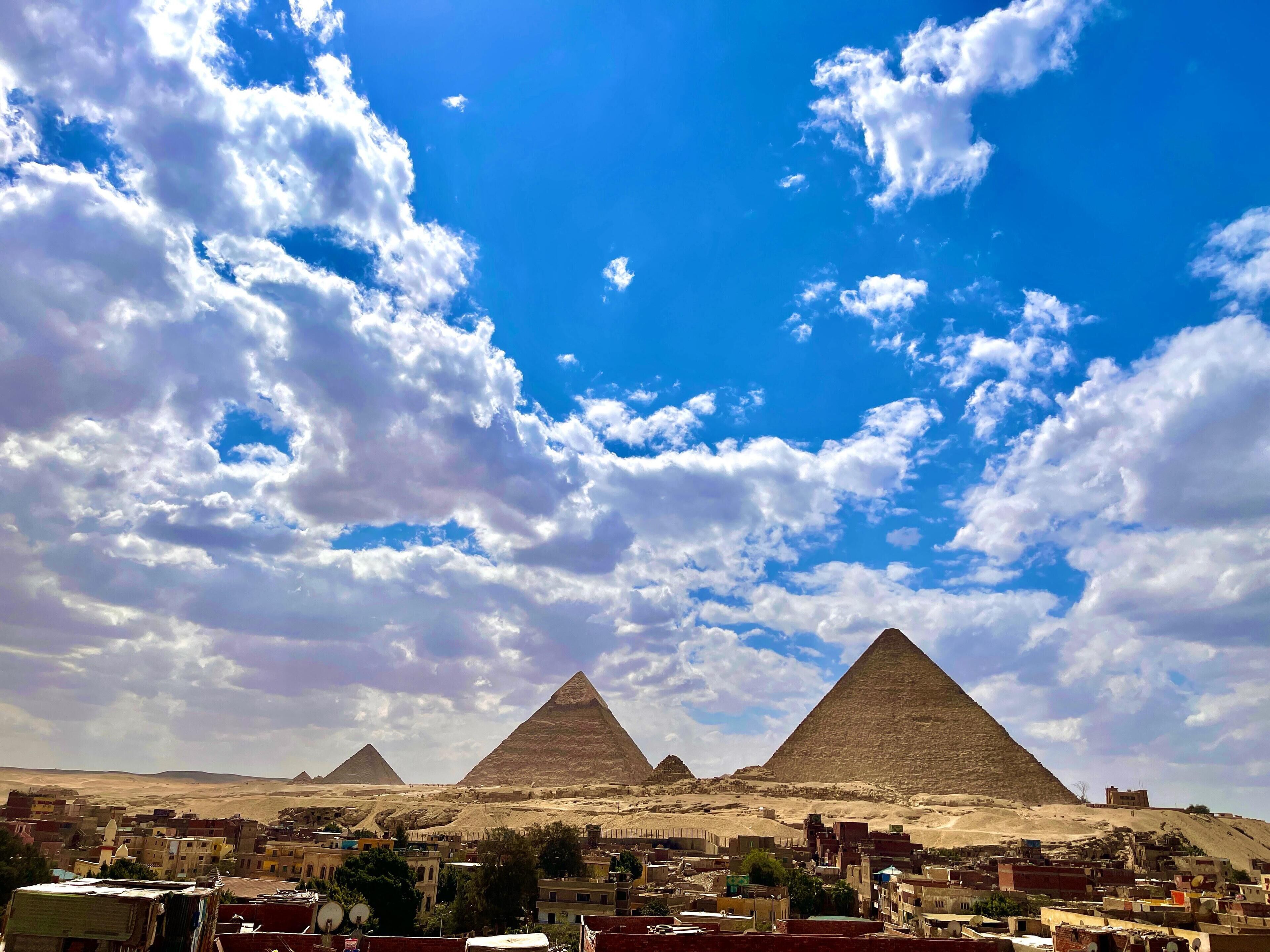 A view of the pyramids with a clear sky and clouds.