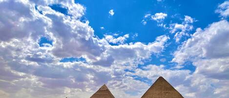 A view of the pyramids with a clear sky and clouds.