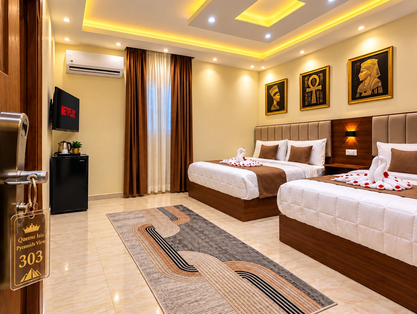 A hotel room with two beds, a flat-screen TV, a minibar, and a view of the pyramids.