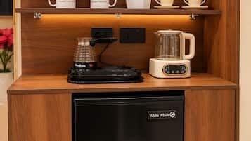 A compact kitchenette with a coffee maker, a kettle, and a refrigerator labeled 'White Whale.'