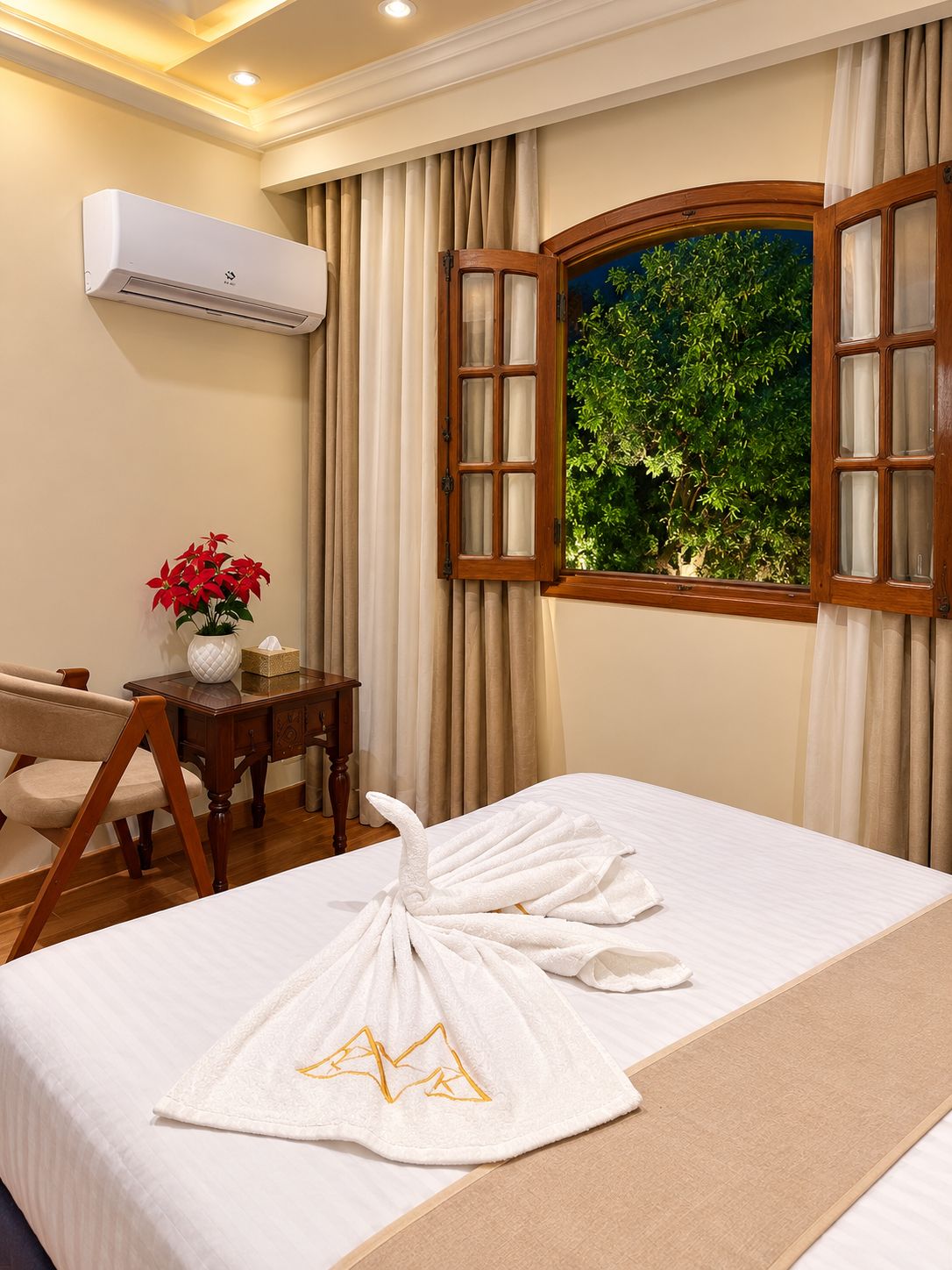 Habitación de hotel con una cama, un escritorio con silla, aire acondicionado y una ventana con cortinas.