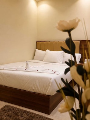A hotel room with a bed, a wooden headboard, and a brown rug. - Pyramids Kingdom RZ Hotel  (Giza)