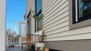 A residential building with a wooden deck, a bench, and potted plants. - Chic 3-bedroom house in Munjoy Hill with off-street parking.   (Portland)