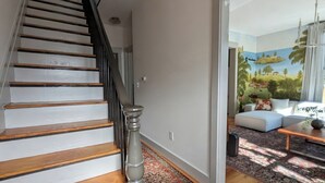 A staircase with wooden steps and a metal balustrade leading to a living area with a sofa, a coffee table, and a patterned rug. - Chic 3-bedroom house in Munjoy Hill with off-street parking.   (Portland)