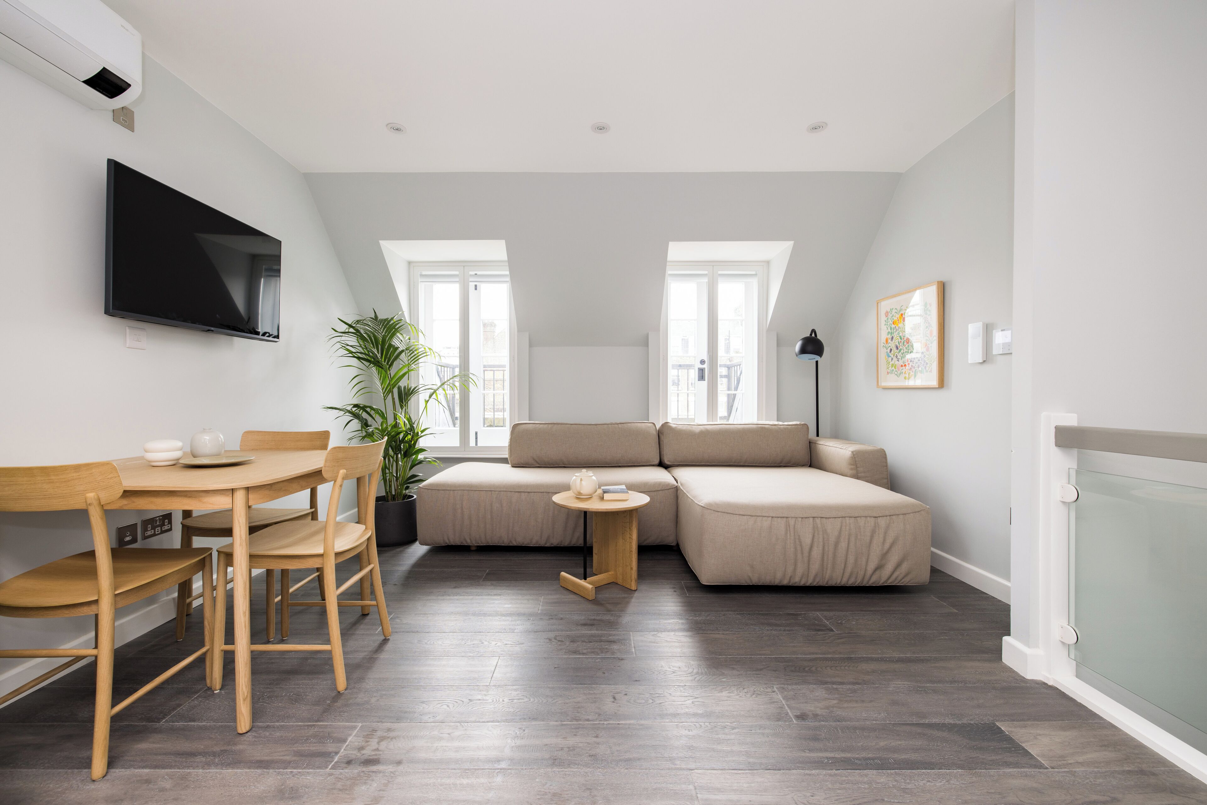 Una sala de estar moderna con una mesa de comedor, sofá y televisor montado en la pared.