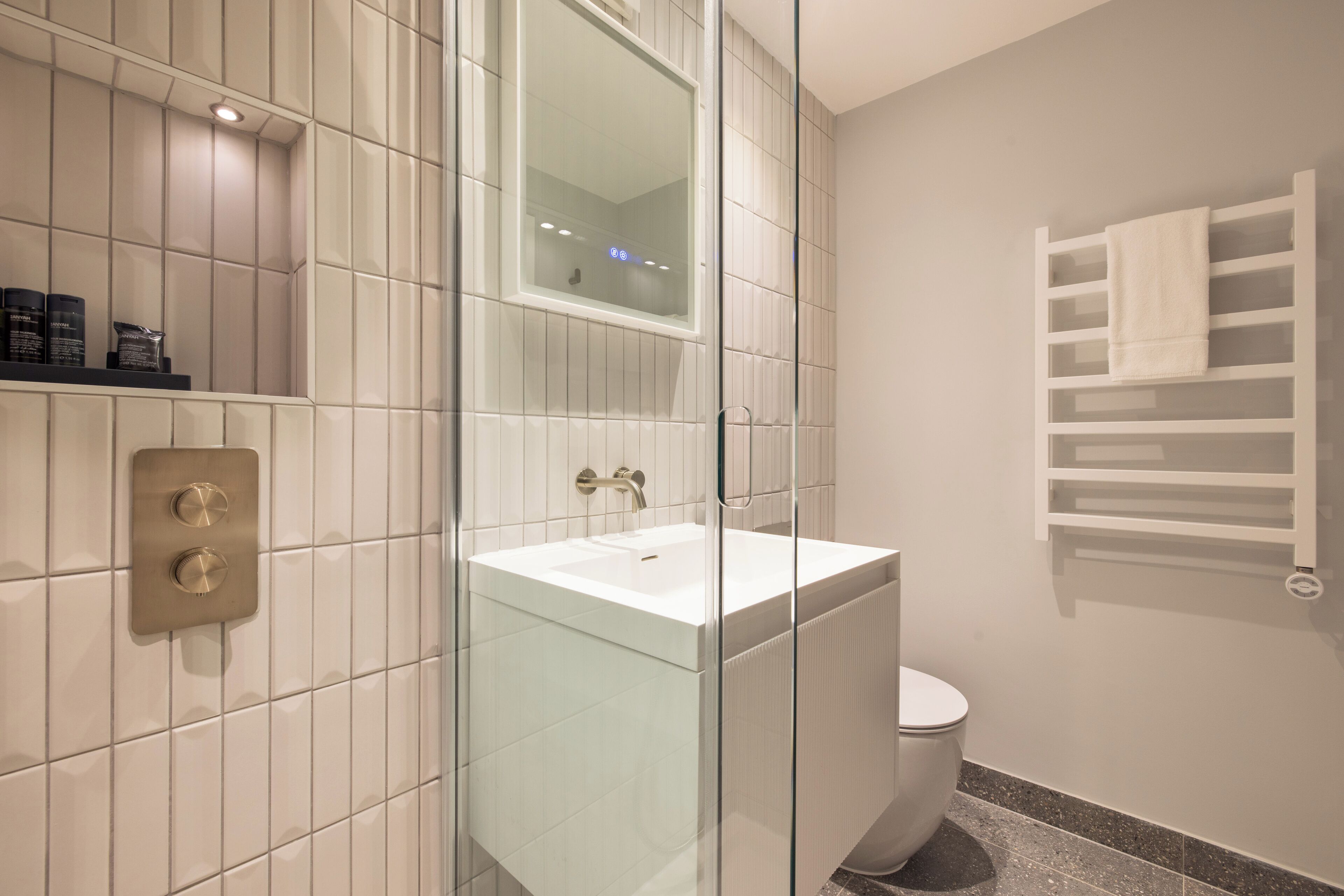 A modern bathroom with a glass-enclosed shower, a white sink, and a toilet.