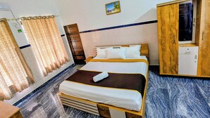 Una camera d'albergo con un letto, un armadio, una scrivania e una finestra con tende.