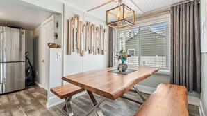 Une cuisine moderne avec une table à manger en bois, des bancs, un réfrigérateur encastré et un luminaire décoratif.