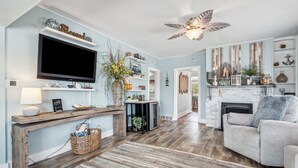 Un salon avec une cheminée, un téléviseur et un ventilateur de plafond.