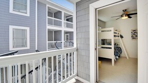 A multi-level house with a balcony, a bedroom with bunk beds, and a ceiling fan.