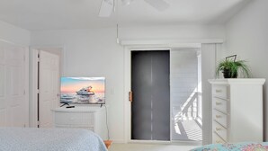 A bedroom with a bed, a dresser, a television, and a sliding door.