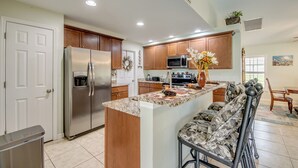 A modern kitchen with wooden cabinets, stainless steel appliances, and a central island. - 4 Bedroom Fresh Water Canal Home with Saltwater Pool and Hot Tub! (Cape Coral, FL)