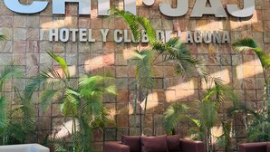 Un muro de piedra con el texto "CHI. JAJ HOTEL Y CLUB DE AGUA" y varias plantas en macetas.